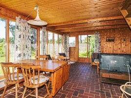 Una cabaña de madera con comedor, televisión y ventanas amplias.