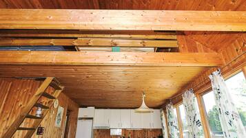 A wooden interior with a kitchen area, including cabinets, a stove, and a refrigerator.