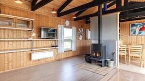 A wooden interior with a fireplace, wooden floors, and a dining area.