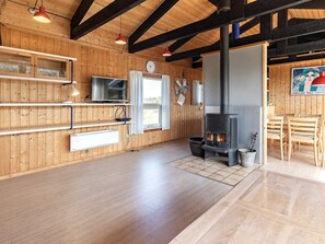 A wooden interior with a fireplace, wooden floors, and a dining area.