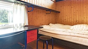 A compact bedroom with a bed, a desk with a chair, and a window.