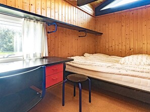 A compact bedroom with a bed, a desk with a chair, and a window.