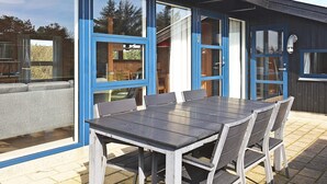 An outdoor dining area with a table and chairs, large windows, and a door. - 8 Person Holiday Home in Vestervig (Vestervig)