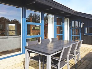 An outdoor dining area with a table and chairs, large windows, and a door. - 8 Person Holiday Home in Vestervig (Vestervig)