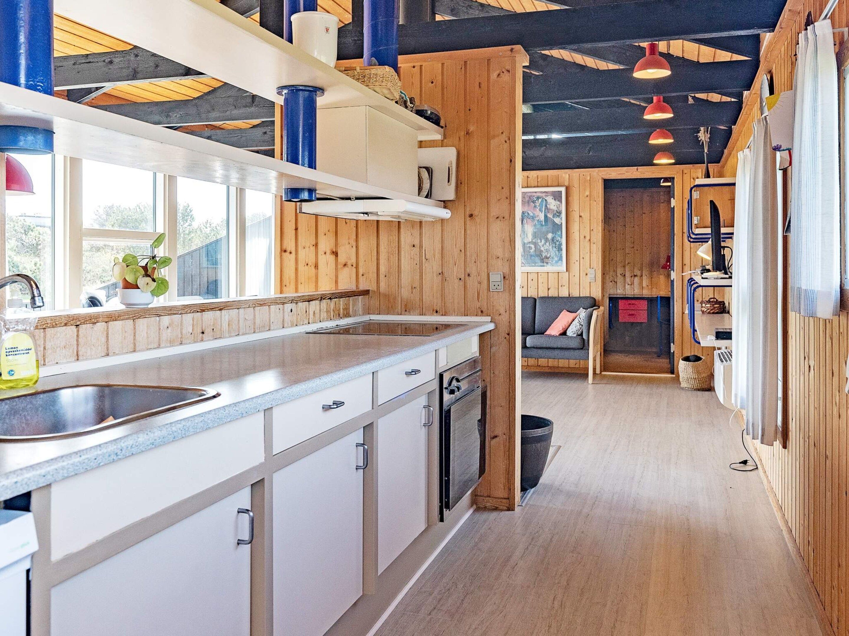A modern kitchen with wooden accents, a built-in dishwasher, and a large window providing natural light.