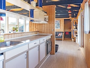 A modern kitchen with wooden accents, a built-in dishwasher, and a large window providing natural light.