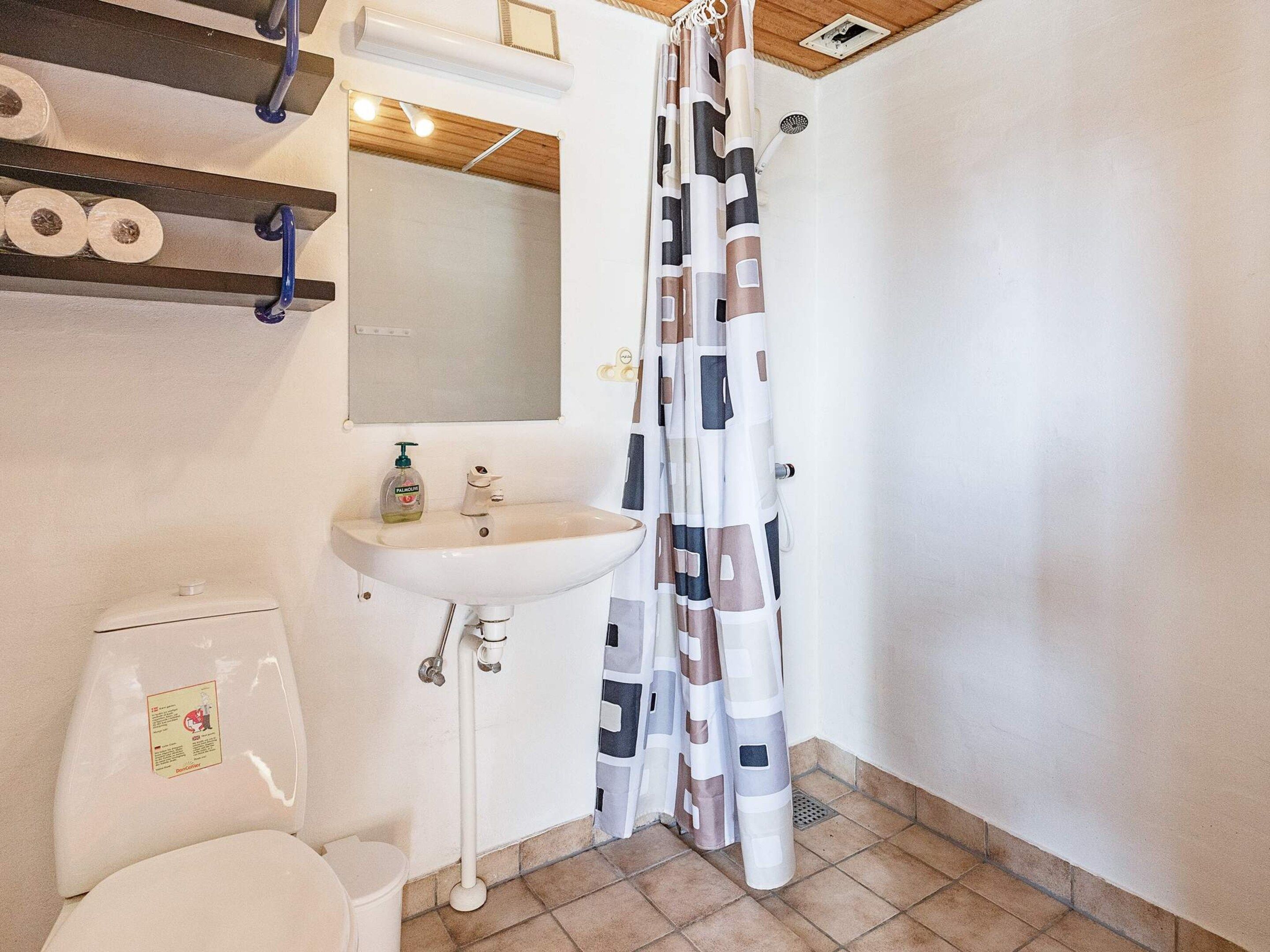 Une salle de bain équipée de toilettes, d’un lavabo et d’un rideau de douche.