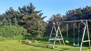 A wooden swing set in a grassy area with trees in the background.