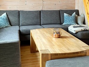 A modern living room with a grey sectional sofa, a wooden coffee table, and a patterned throw pillow. - 8 Person Holiday Home in Trysil (Trysil)