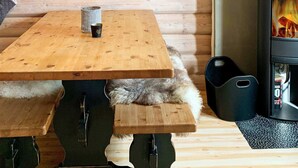 A wooden table with a cup and a bench in a cabin with a wood-burning stove. - 8 Person Holiday Home in Trysil (Trysil)