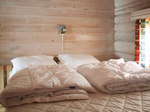 A wooden cabin room with a bed, a wall-mounted light, and a window with curtains. - 8 Person Holiday Home in Trysil (Trysil)
