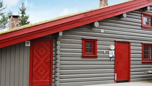 A log cabin with two red doors and windows, a stone chimney, and a small porch. - 8 Person Holiday Home in Trysil (Trysil)