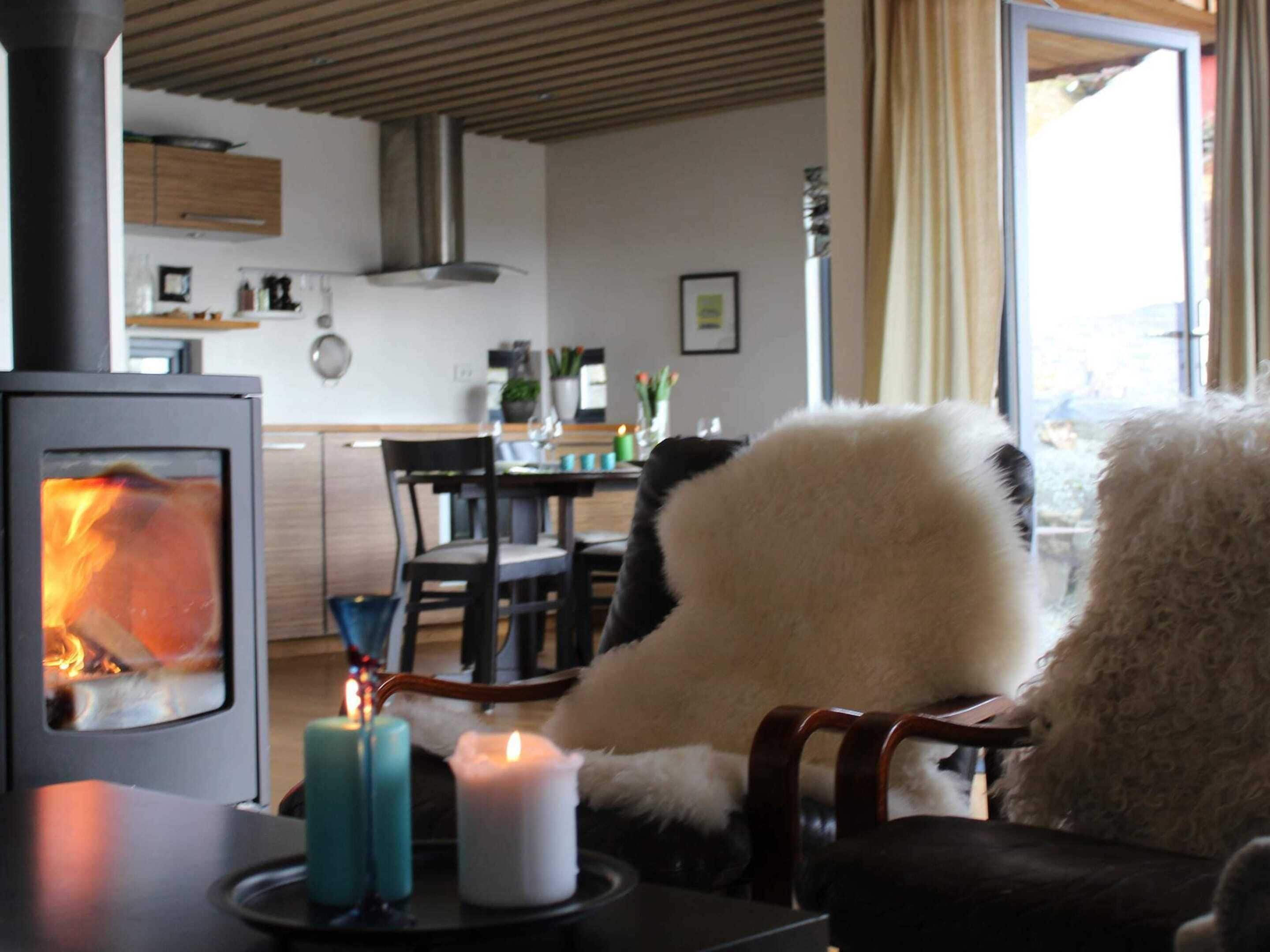 A cozy living room with a fireplace, a dining area, and a kitchen in the background.