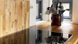 A modern kitchen with a wooden wall, a glass cooktop, and a window with a view. - Holiday Home in Jelsa (Suldal)