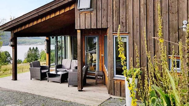 A wooden house with a covered porch, outdoor seating, and a view of a lake. - Holiday Home in Jelsa (Suldal)