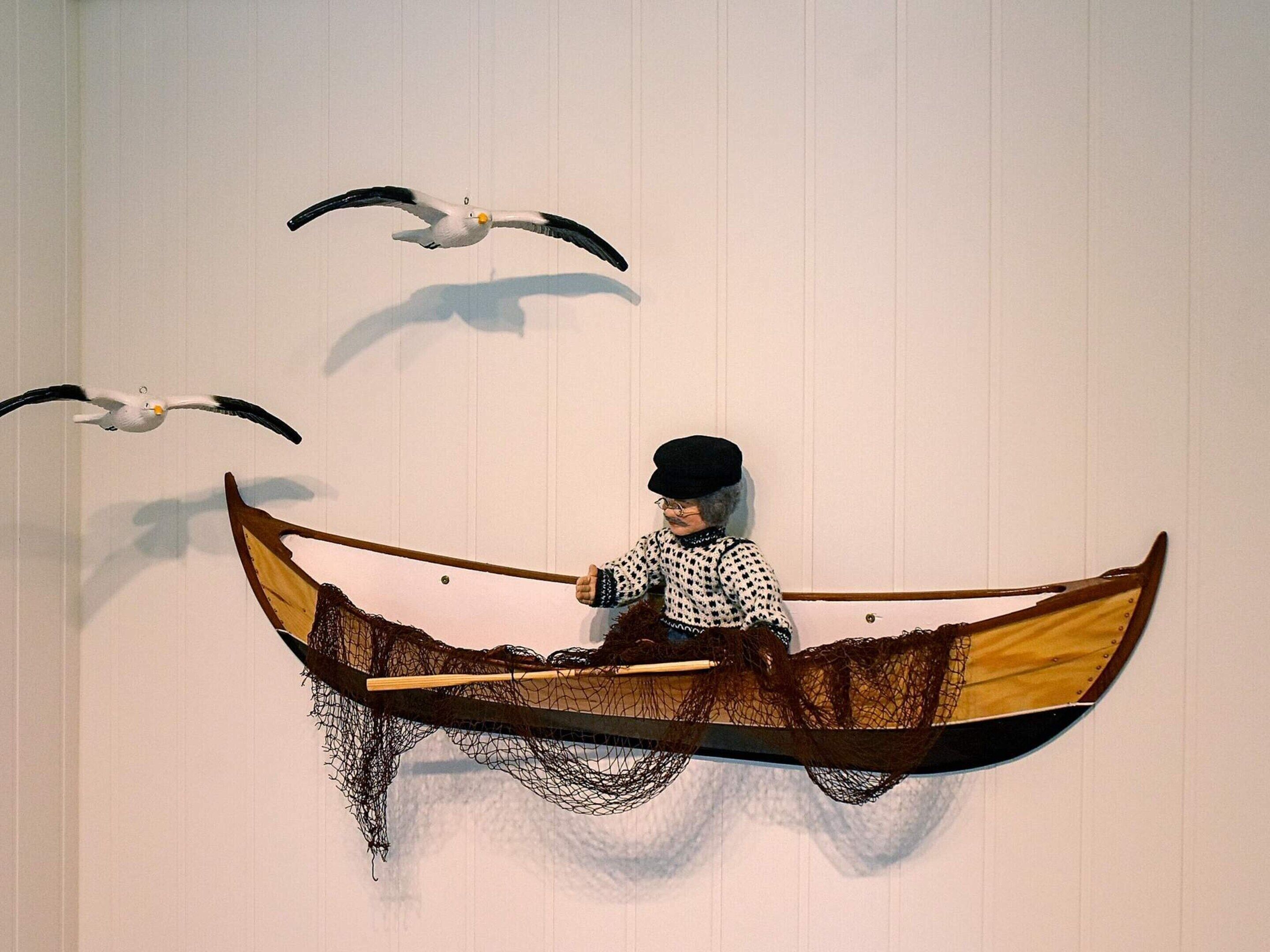 A person in a boat with a net, surrounded by seagulls.