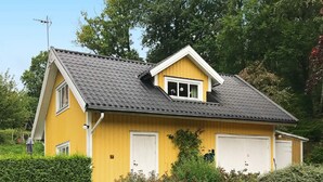 A yellow house with a dark roof, two garage doors, and a chimney. - 5 Person Holiday Home in Haverud-by Traum (Håverud)