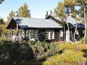 A rustic wooden cabin with a sloped roof, large windows, and a porch area. - 4 Star Holiday Home in Rennebu (Rennebu)