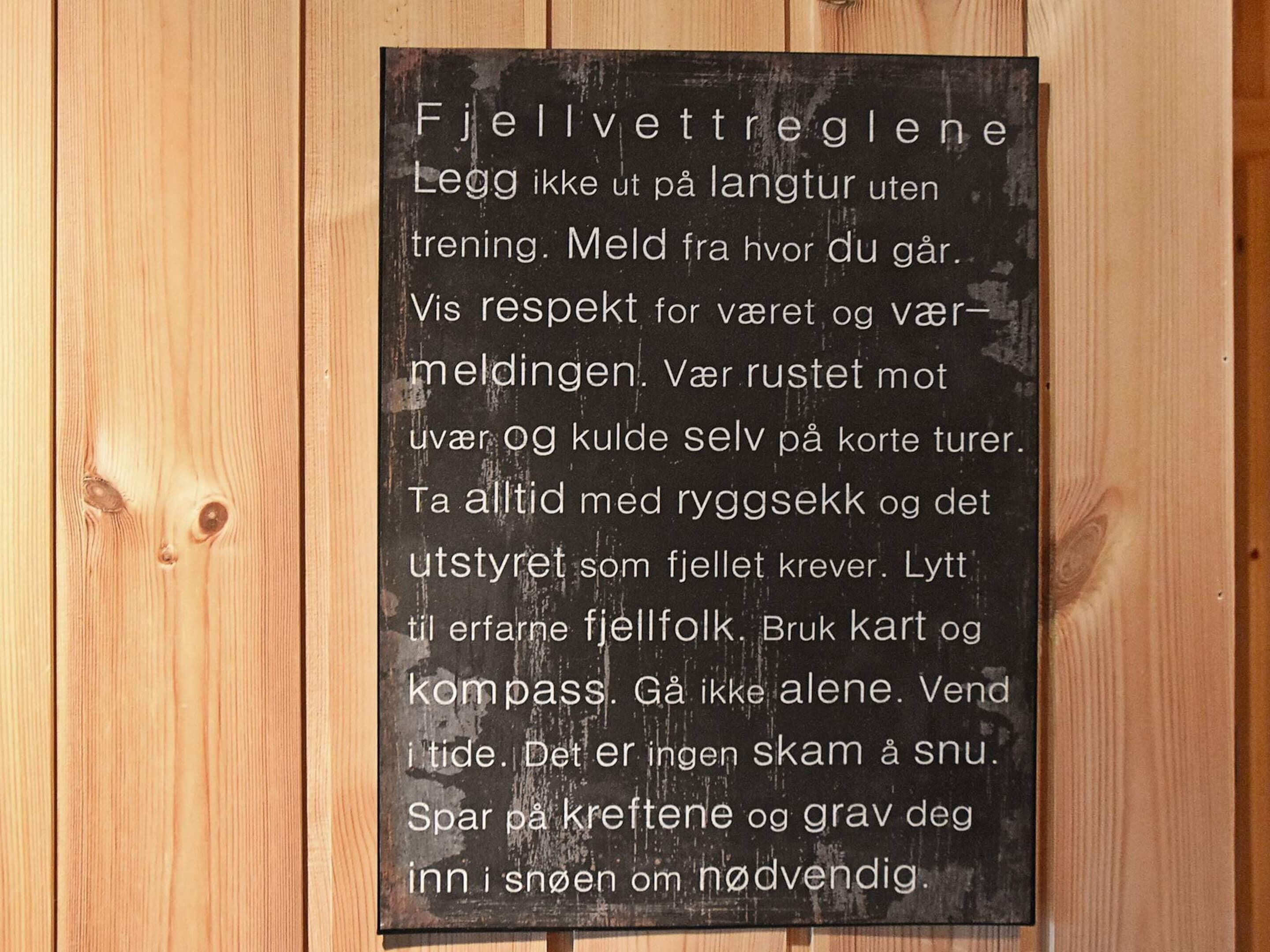 Une enseigne avec du texte dans une langue étrangère, fixée sur une surface en bois.
