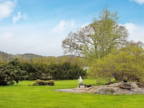 A statue on a rock in a grassy field with trees and a hill in the background. - Holiday Home in Askeröarna (Hjaelteby)
