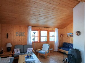 A wooden cabin interior with a sofa, armchair, table, and a stove. - 4 Person Holiday Home in Foldereid (Nærøysund)