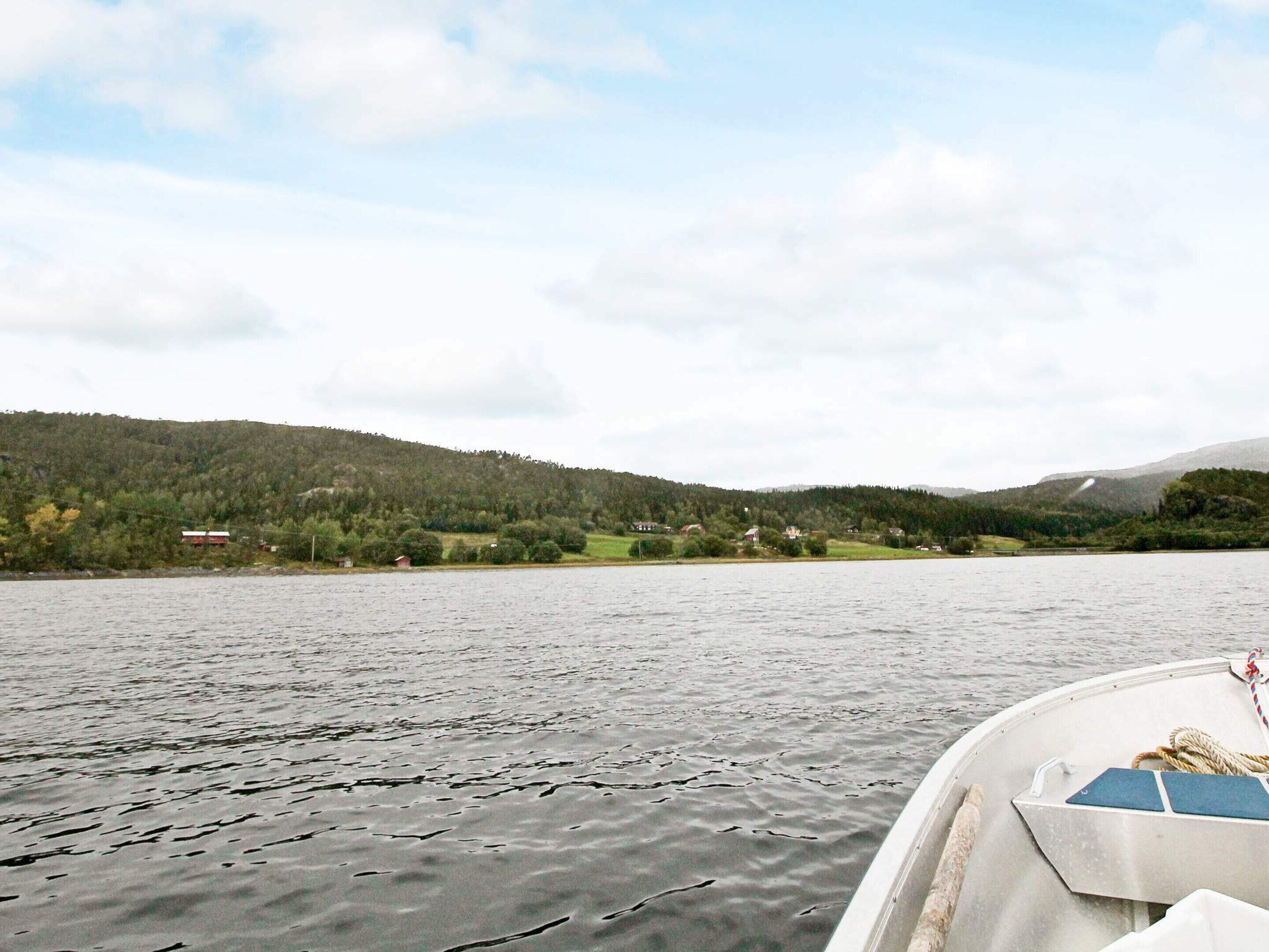 A boat on a lake with a forested hillside in the background.