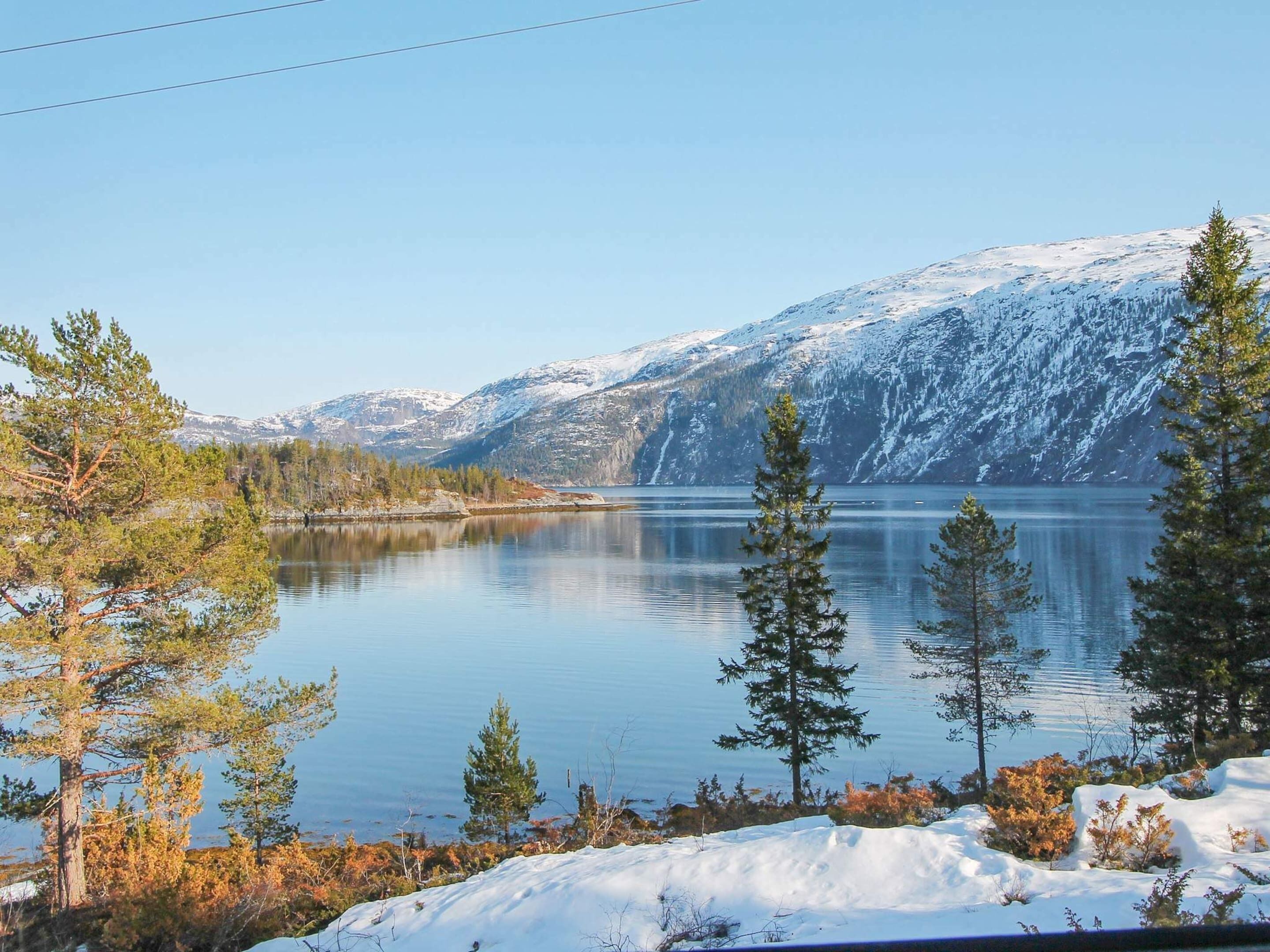 Un lago tranquilo rodeado de montañas y árboles cubiertos de nieve.