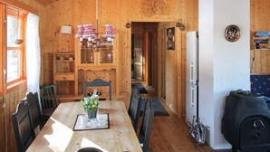 A wooden interior with a dining table, chairs, a chandelier, a refrigerator, and a grill. - 4 Person Holiday Home in Foldereid (Nærøysund)