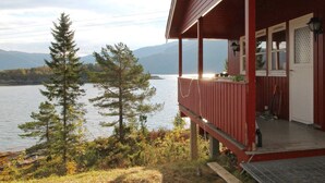 A wooden cabin with a porch overlooking a lake and mountains. - 4 Person Holiday Home in Foldereid (Nærøysund)