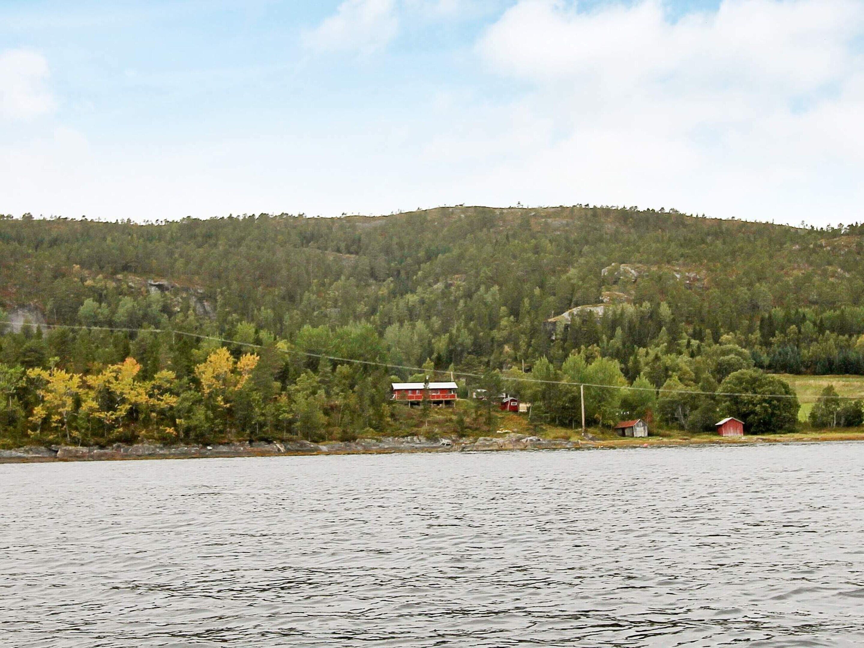 Udsigt over en sø med en rød hytte og en mindre rød bygning på en bakke.
