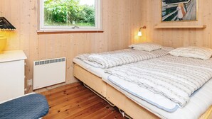 Une chambre avec un lit, une fenêtre, un radiateur et un tableau accroché au mur.