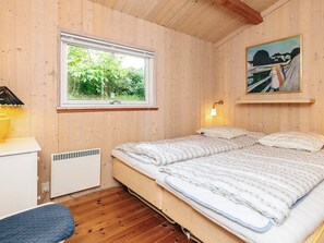 Un dormitorio con cama, ventana, radiador y un cuadro en la pared.