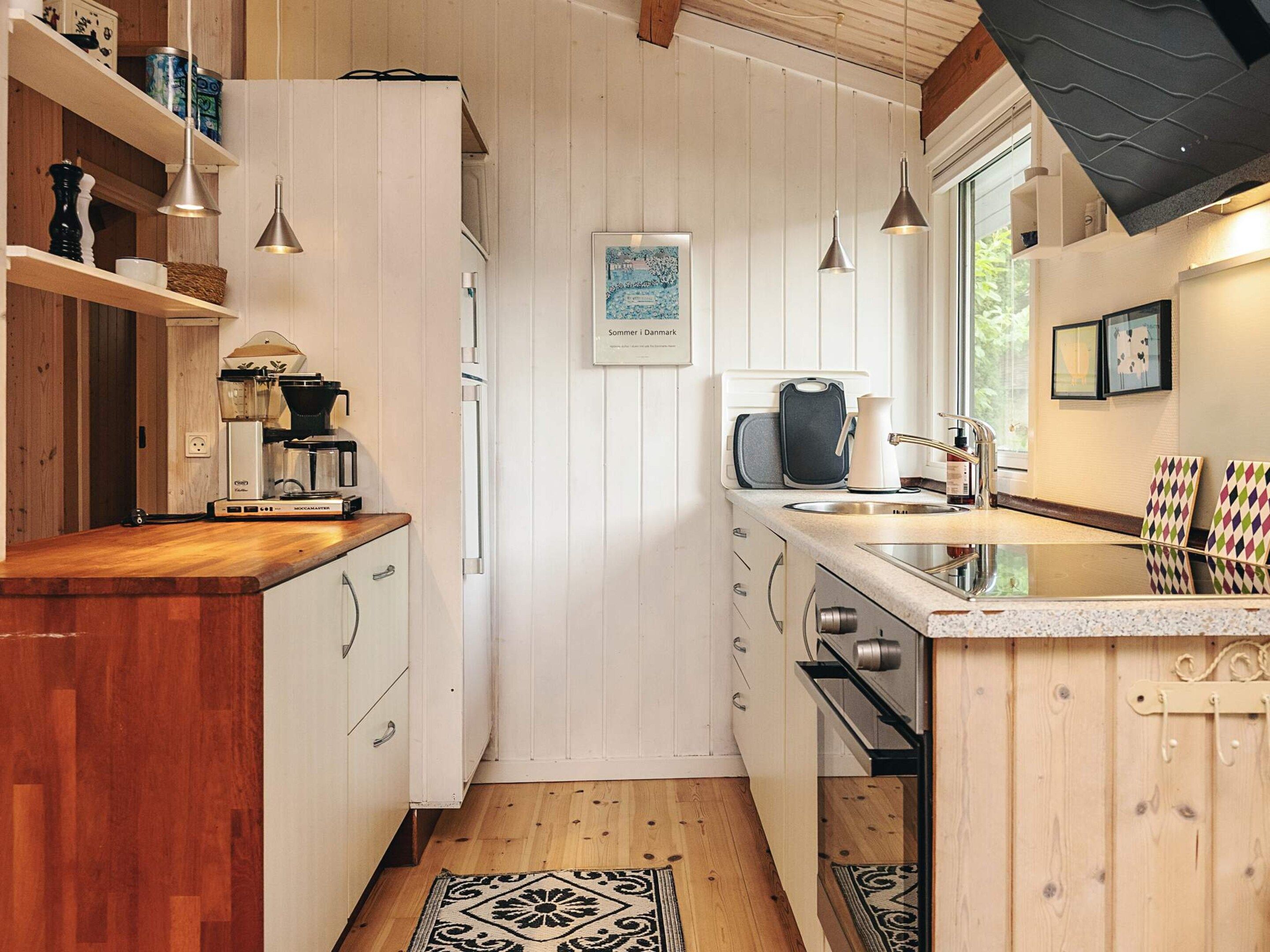 Une cuisine compacte avec des meubles en bois, une machine à café et des luminaires suspendus.