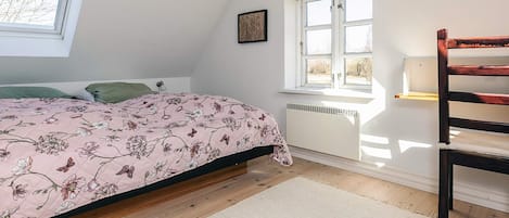 A bedroom with a bed, a window, a radiator, and a chair.