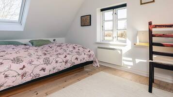A bedroom with a bed, a window, a radiator, and a wooden chair.