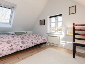 A bedroom with a bed, a window, a radiator, and a wooden chair. - 4 Star Holiday Home in Humble (Sydlangeland)