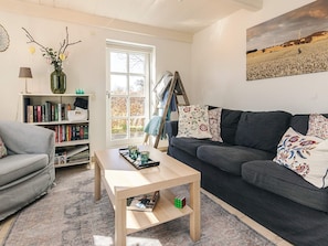 A living room with a sofa, a coffee table, a bookshelf, and a painting on the wall.