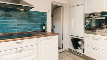 A kitchen with white cabinets, a stainless steel range hood, and a blue-tiled backsplash.