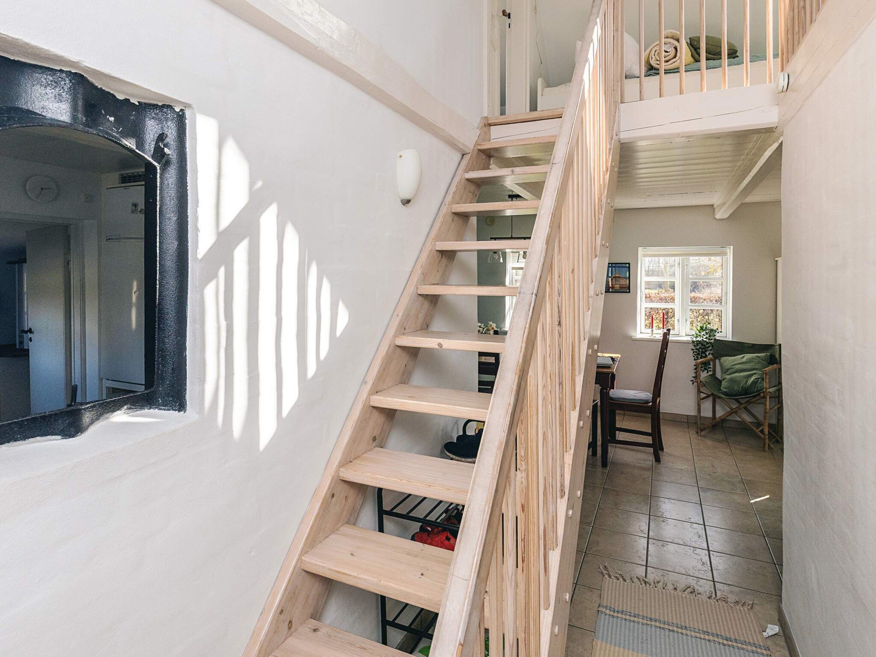 A staircase leading to a second floor with a view of a window and a chair.