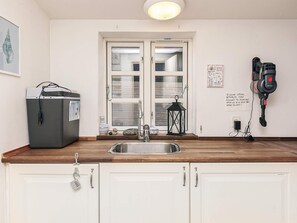 A kitchen with a sink, a refrigerator, a window, and a power outlet. - 4 Star Holiday Home in Humble (Sydlangeland)