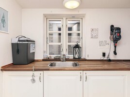 A kitchen with a sink, a refrigerator, a window, and a power outlet.