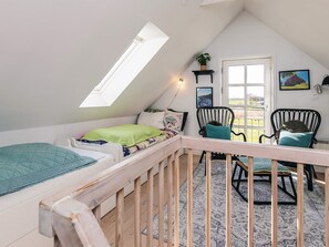 A cozy attic bedroom with a sloped ceiling, a skylight, a bed, two chairs, a small table, and a door leading outside. - 4 Star Holiday Home in Humble (Sydlangeland)