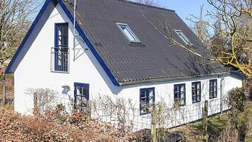 Ein zweistöckiges Haus mit einem steilen Satteldach, zahlreichen Fenstern und einem sichtbaren Schornstein.