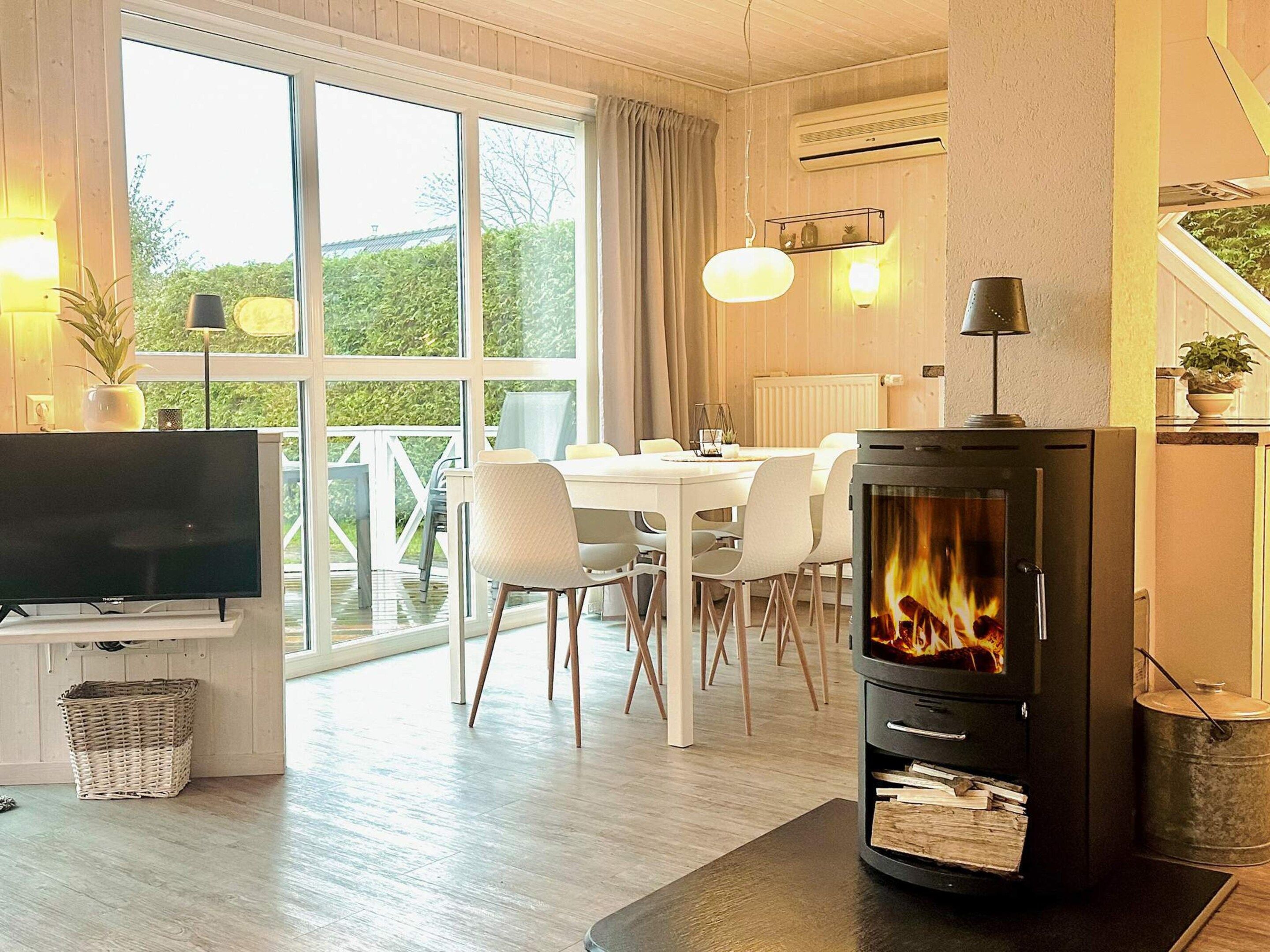 A modern living room with a fireplace, dining area, and large windows.