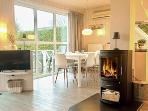A modern living room with a fireplace, dining area, and large windows. - Holiday Home in Gelting (Gelting)