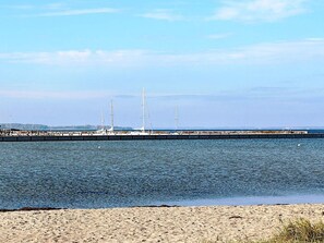 A sandy beach with a calm sea and a pier with boats. - Holiday Home in Gelting (Gelting)
