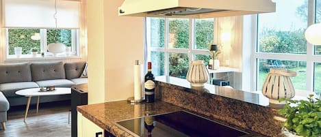 A modern kitchen with a built-in stove, a large window, and a view of the outdoors.