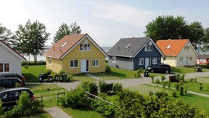 A residential area with houses, a paved driveway, and parked cars. - Holiday Home in Gelting (Gelting)