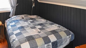 A bed with a patchwork quilt, a wooden bench, and a wall-mounted lamp. - 5 Person Holiday Home in Bud-by Traum (Hustadvika)