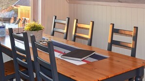 A dining area with a wooden table, six chairs, a potted plant, and a speaker. - 5 Person Holiday Home in Bud-by Traum (Hustadvika)